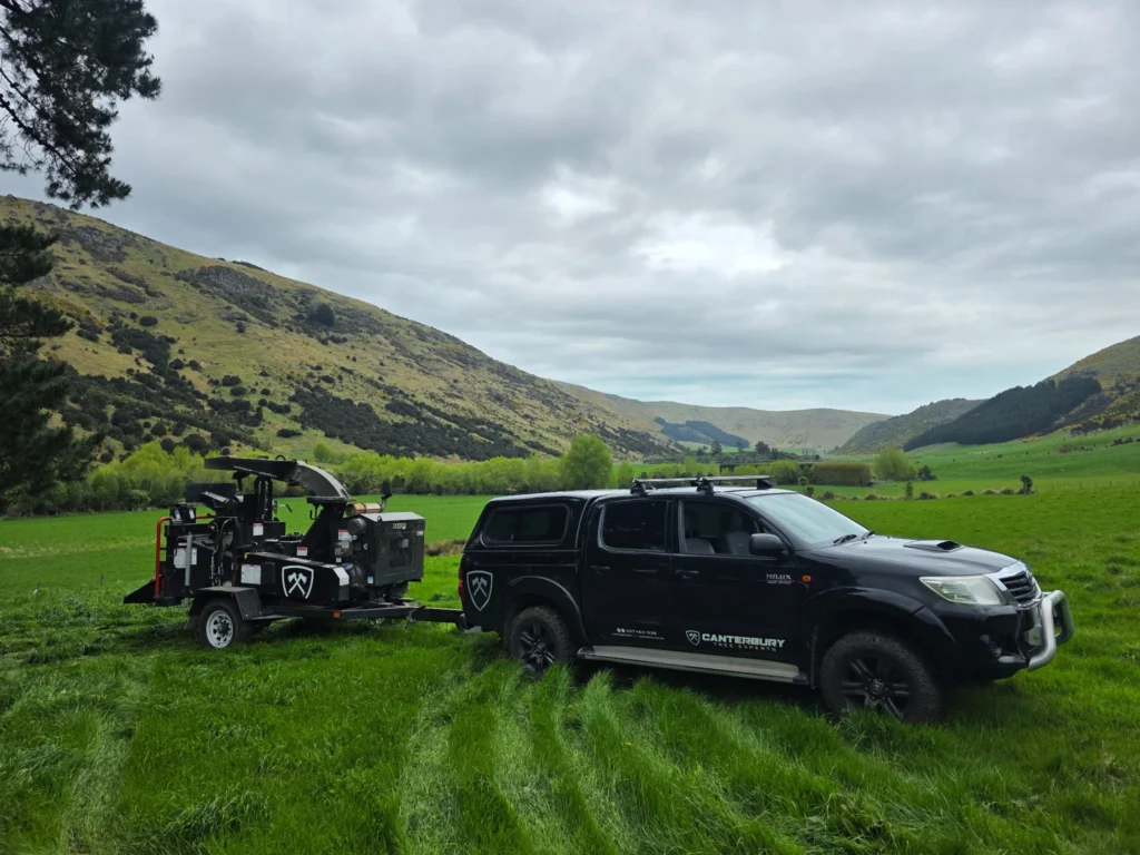 wood chipper being towed by Canterbury tree experts Ute in a paddock with green grass
